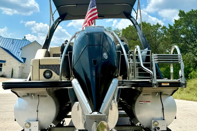Slide: The Image of 2021 Barletta L25UC pontoon boat with American flag, parked outdoors. - 21