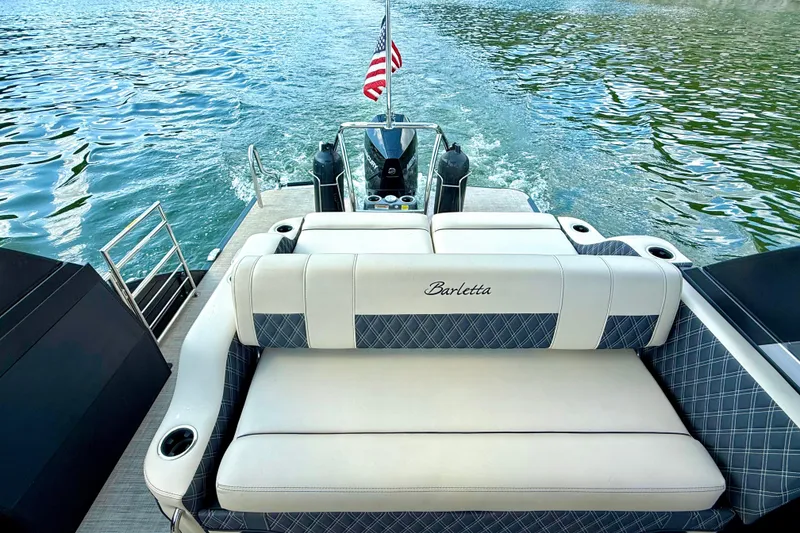 Slide: The Image of 2021 Barletta L25UC pontoon boat with plush seating on a serene lake. - 28