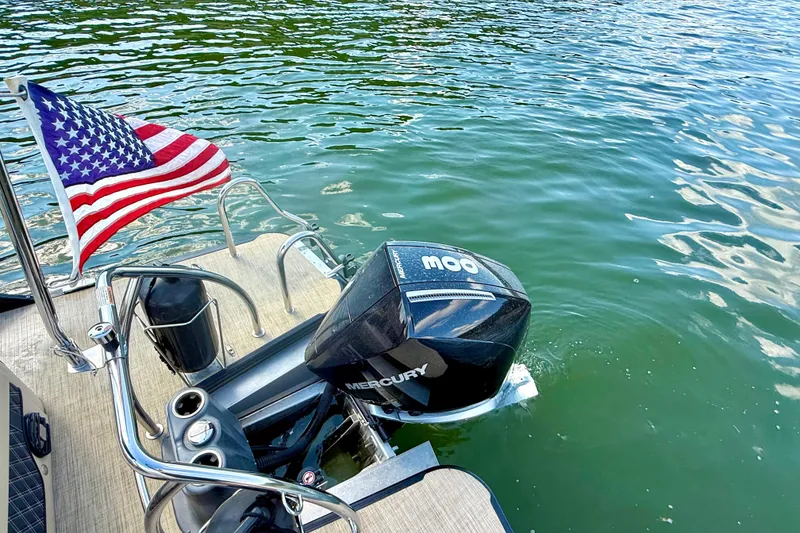 Slide: The Image of 2021 Barletta L25UC boat with Mercury engine and American flag on water. - 30