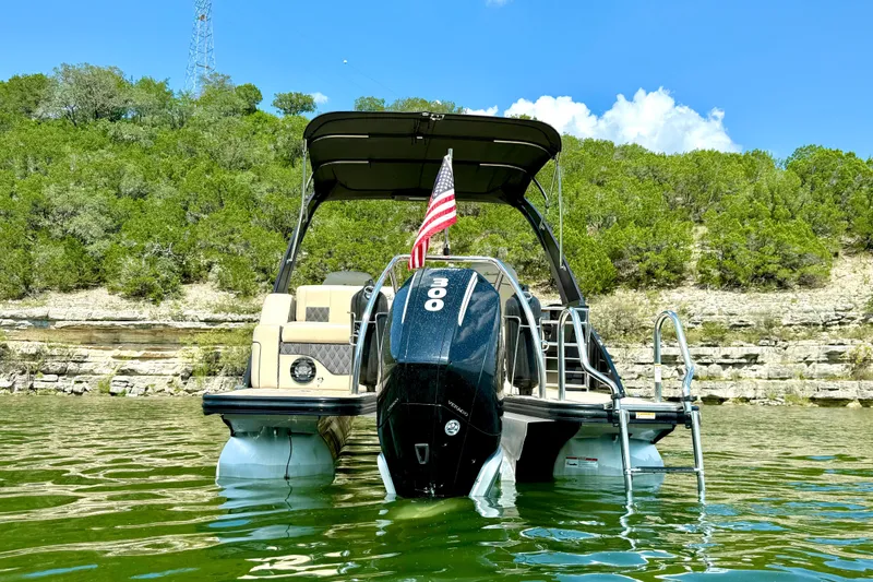 Slide: The Image of 2021 Barletta L25UC pontoon boat on a lake, with lush green shoreline. - 4