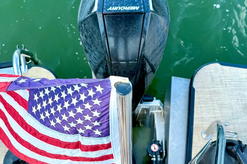 Slide: The Image of 2021 Barletta L25UC boat with American flag and Mercury engine on water. - 53