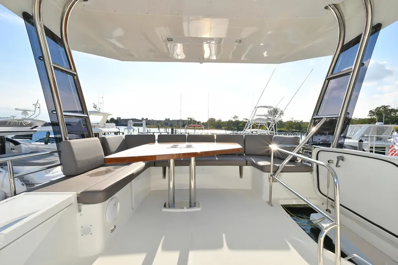 Slide: The Image of Flybridge seating area on a 2018 Prestige 560 Fly yacht, featuring a wooden table and cushioned benches. - 11