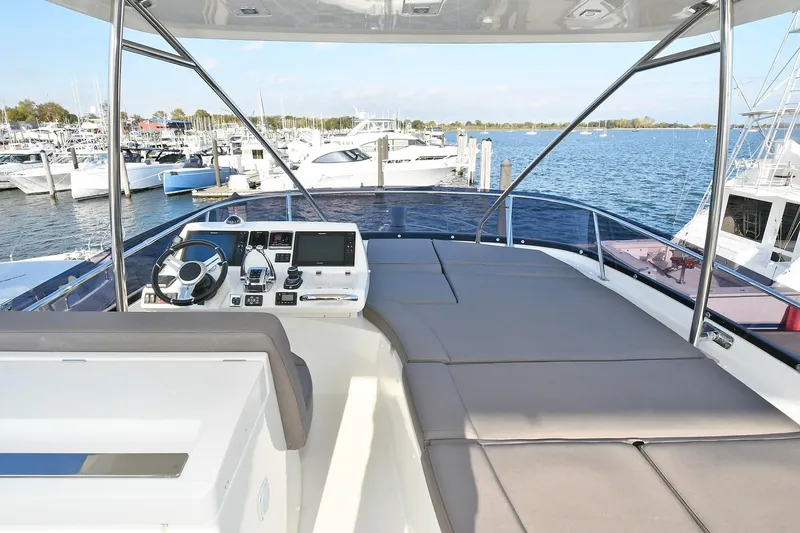Slide: The Image of Flybridge of 2018 Prestige 560 Fly yacht with helm and sunbathing area, docked at marina. - 15