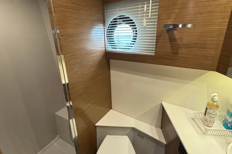 Slide: The Image of Bathroom interior of 2019 Cruisers Yachts 42 Cantius with wooden accents and porthole window. - 50