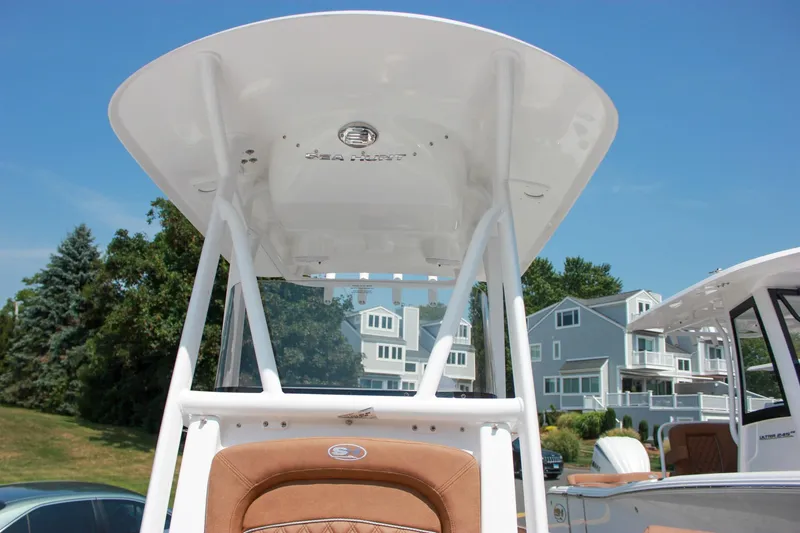 Slide: The Image of 2026 Sea Hunt Ultra 219 boat with T-top, docked near waterfront homes. - 16
