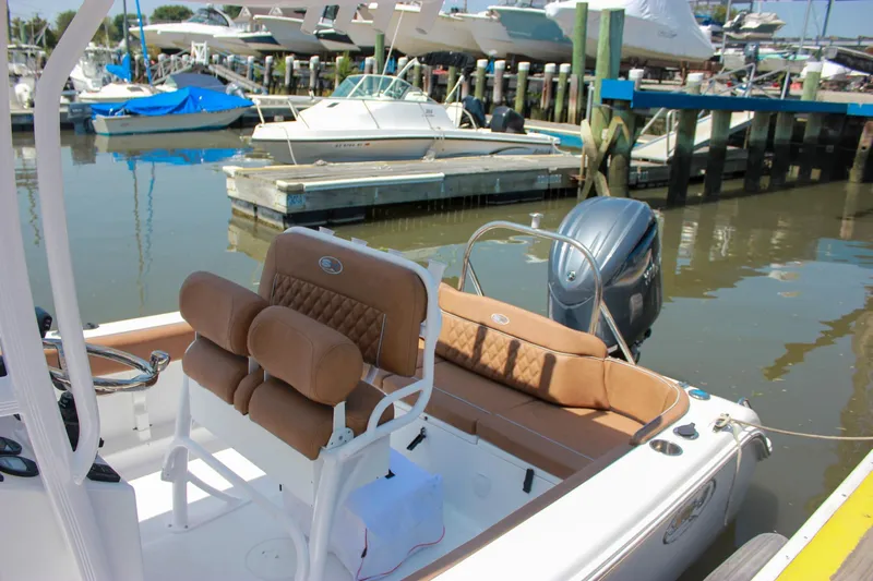 Slide: The Image of 2026 Sea Hunt Ultra 219 boat docked, featuring tan seating and outboard motor. - 2