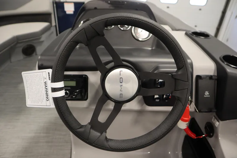 Slide: The Image of Steering wheel of 2026 Lowe LS 170 boat with dashboard controls and warning tag. - 18