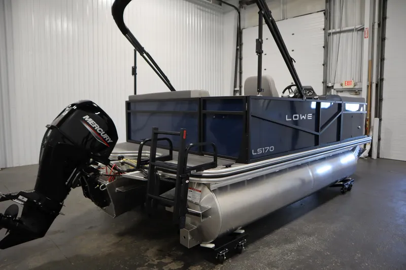 Slide: The Image of 2026 Lowe LS 170 pontoon boat with Mercury outboard motor in a garage setting. - 4