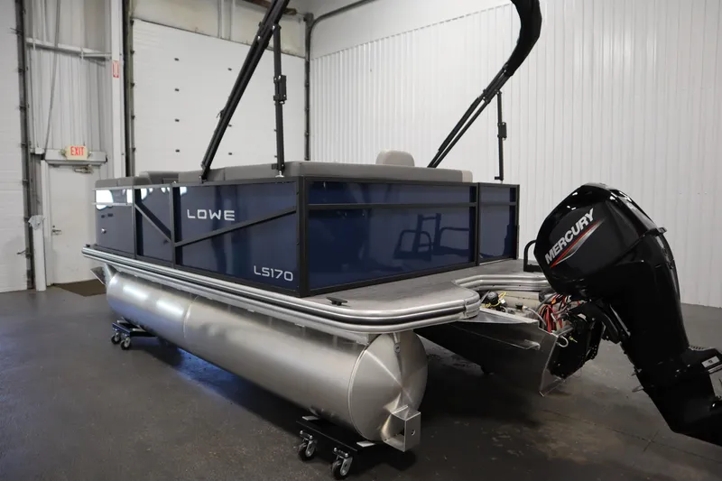 Slide: The Image of 2026 Lowe LS 170 pontoon boat with Mercury outboard motor in a garage setting. - 6