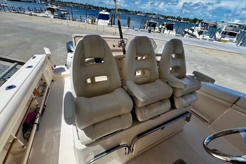 Slide: The Image of 2015 Grady-White Canyon 336 boat interior with three cushioned seats, docked by the marina. - 19