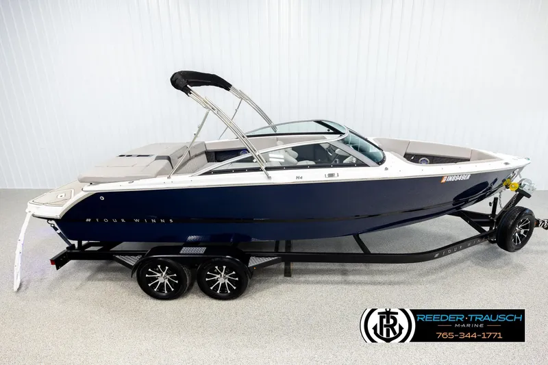 The Image of 2024 Four Winns H4 boat on trailer, displayed indoors at Reeder-Trausch Marine. - 1