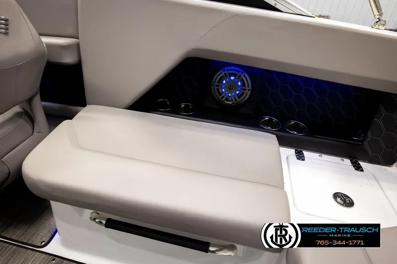 Slide: The Image of 2024 Four Winns H4 boat interior with cushioned seating and blue LED speaker lighting. - 27