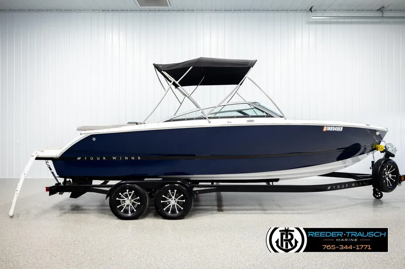 Slide: The Image of 2024 Four Winns H4 boat on trailer in showroom, featuring sleek design and canopy. - 5