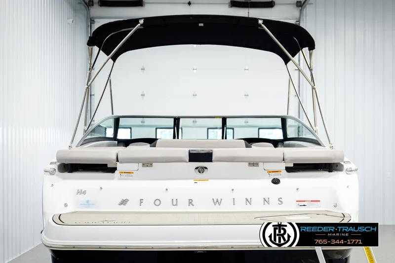 Slide: The Image of 2024 Four Winns H4 boat rear view with canopy in showroom. - 7
