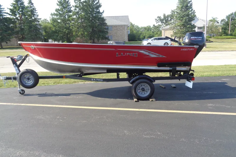 The Image of 2026 Lund 1400 Fury Tiller boat on trailer, red exterior, parked outdoors. - 1