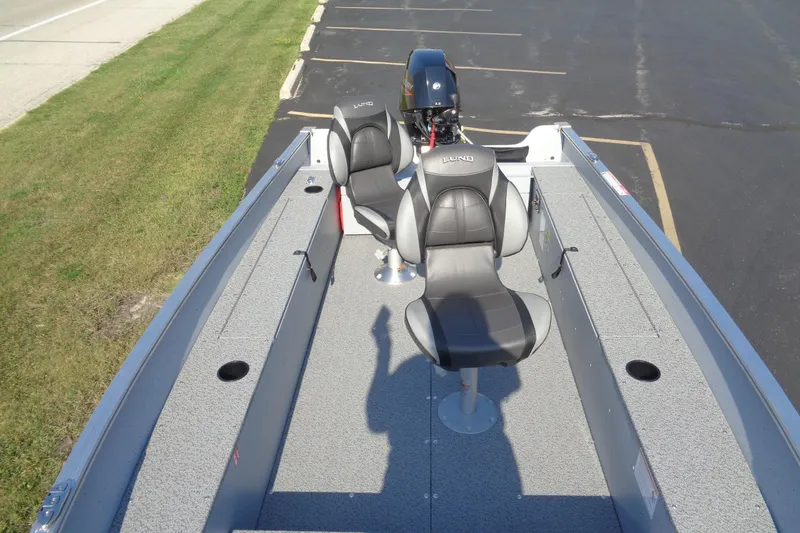 Slide: The Image of 2026 Lund 1400 Fury Tiller boat with two seats and motor, parked on pavement. - 8