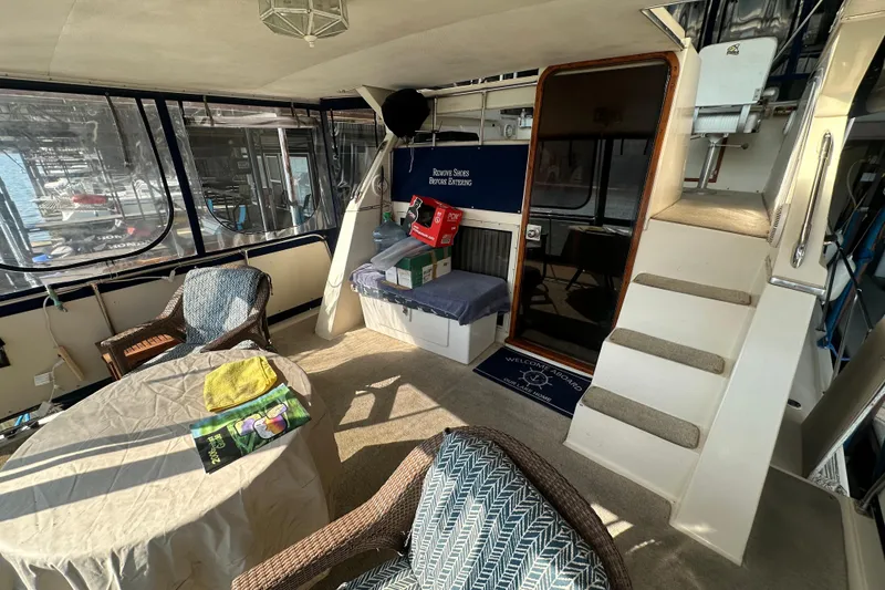 Slide: The Image of 1985 Chris-Craft 426 Catalina interior with seating, table, and stairs in a cozy cabin setting. - 12