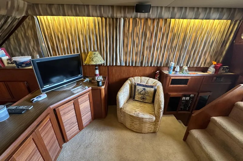Slide: The Image of 1985 Chris-Craft 426 Catalina interior with TV, wicker chair, and wooden cabinetry. - 23