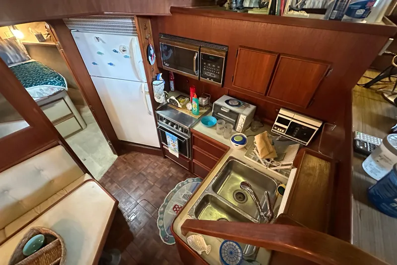 Slide: The Image of 1985 Chris-Craft 426 Catalina yacht kitchen with appliances, sink, and dining area. - 28