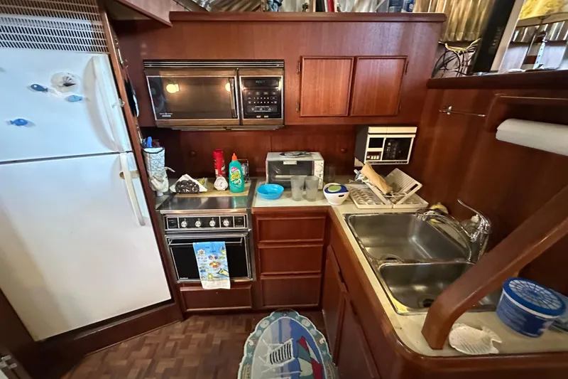 Slide: The Image of 1985 Chris-Craft 426 Catalina kitchen with appliances, wooden cabinets, and a stainless steel sink. - 29