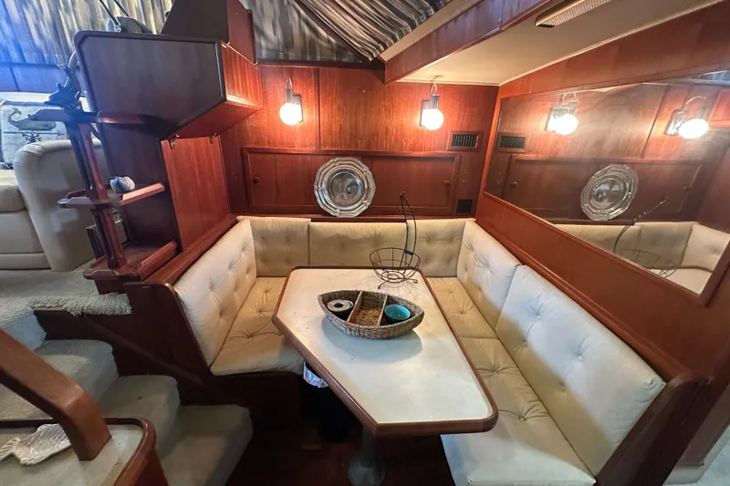Slide: The Image of 1985 Chris-Craft 426 Catalina interior with cozy dining area, wooden accents, and soft lighting. - 32