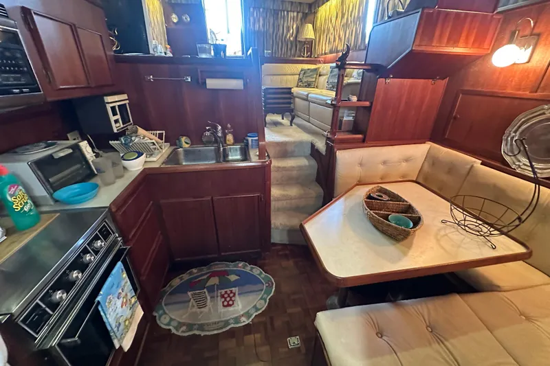 Slide: The Image of 1985 Chris-Craft 426 Catalina interior with kitchen, dining area, and cozy seating. - 33