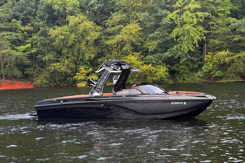 Slide: The Image of 2020 Centurion Ri257 boat cruising on a serene lake with lush green forest backdrop. - 2