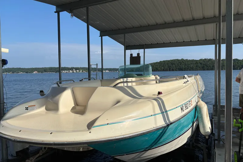 Slide: The Image of 1996 Bayliner 2659 Rendezvous boat docked on a serene lake under a covered slip. - 5