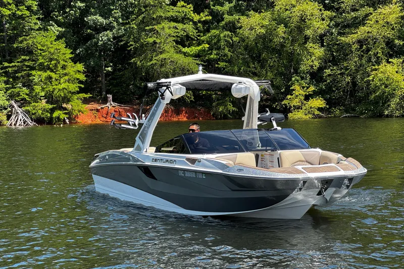 Slide: The Image of 2023 Centurion Fi25 boat cruising on a scenic lake with lush green trees. - 2