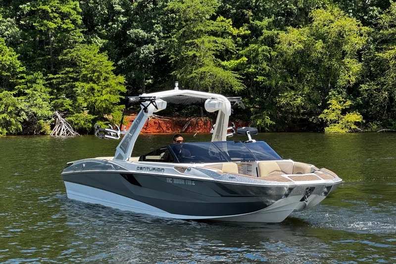Slide: The Image of 2023 Centurion Fi25 boat cruising on a scenic lake with lush green trees. - 4