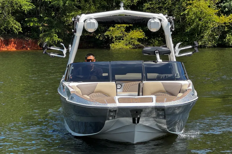 Slide: The Image of 2023 Centurion Fi25 boat cruising on a serene lake with lush greenery. - 5