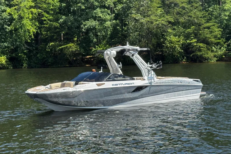 Slide: The Image of 2023 Centurion Fi25 boat on a serene lake with lush green trees. - 7