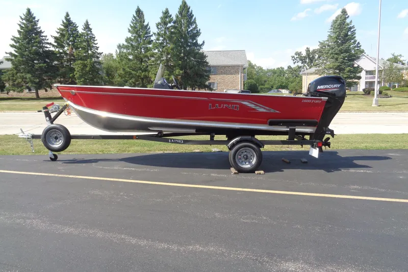 The Image of 2026 Lund 1600 Fury SS boat on trailer, red exterior, parked on asphalt. - 1
