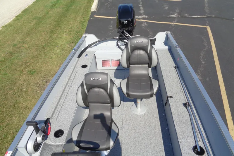 Slide: The Image of 2026 Lund 1600 Fury SS boat interior with two seats and motor, parked on pavement. - 17