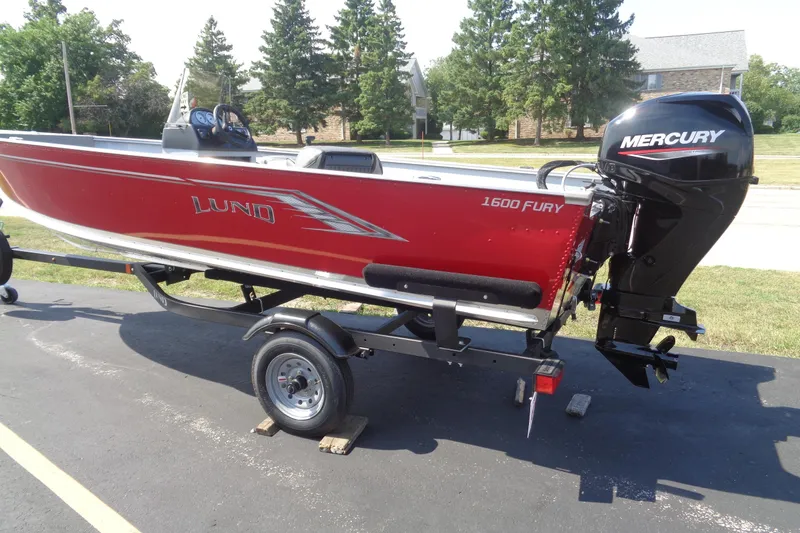 Slide: The Image of 2026 Lund 1600 Fury SS boat with Mercury engine on trailer, parked outdoors. - 2
