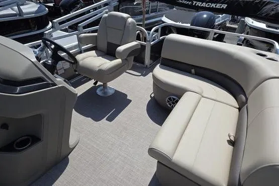 Slide: The Image of 2025 Sun Tracker PB 18 DLX pontoon boat interior with beige seating and steering console. - 10