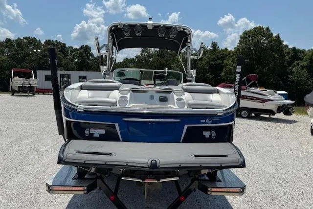 Slide: The Image of 2016 MasterCraft X26 boat, rear view, parked on gravel lot under blue sky. - 11