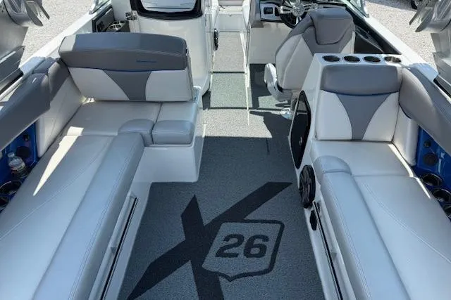 Slide: The Image of 2016 MasterCraft X26 boat interior with gray and white seating, cup holders, and logo on floor. - 14
