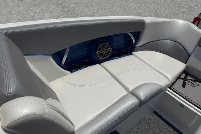 Slide: The Image of 2016 MasterCraft X26 boat interior with white and gray seating, blue accents, and cup holders. - 20