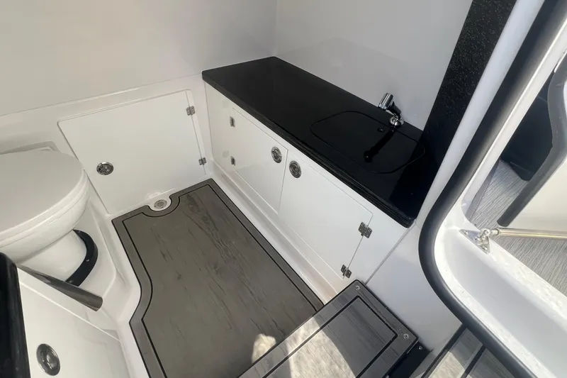 Slide: The Image of 2026 Monterey Elite 27 OB boat bathroom with sleek black countertop and modern fixtures. - 10