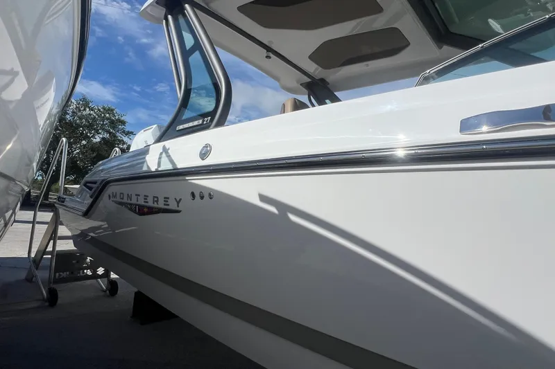 Slide: The Image of 2026 Monterey Elite 27 OB boat, sleek white exterior, docked under clear blue sky. - 23