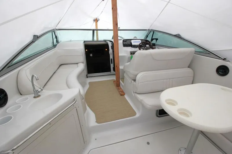 Slide: The Image of 2002 Crownline 290 CR boat interior with seating, helm, and table under a canopy. - 2