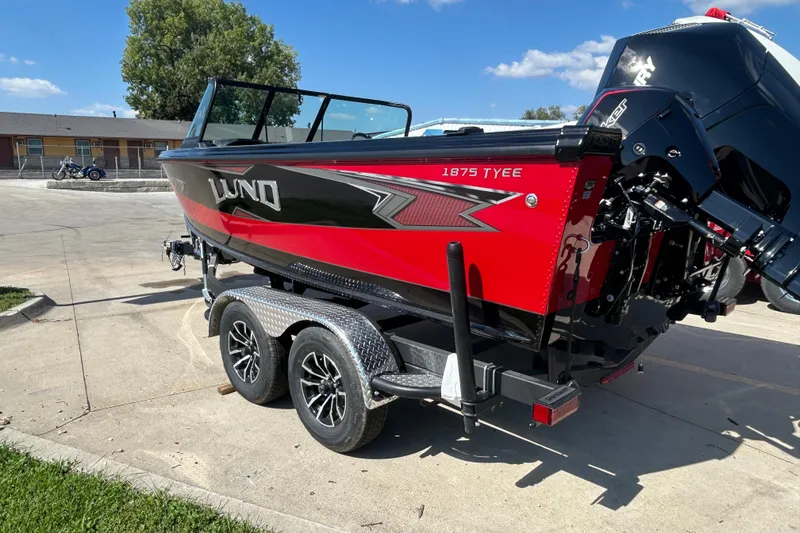 Slide: The Image of 2026 Lund 1875 Tyee boat on trailer, red and black design, parked outdoors. - 12