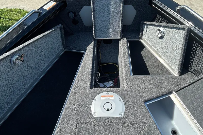 Slide: The Image of 2026 Lund 1875 Tyee boat interior with open storage compartments and carpeted flooring. - 14