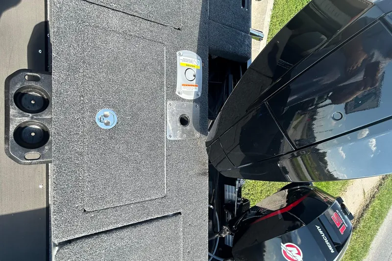 Slide: The Image of 2026 Lund 1875 Tyee boat deck with Mercury engine, featuring cup holders and storage compartments. - 16