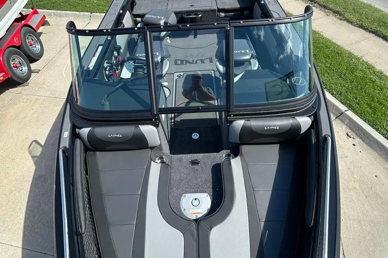 Slide: The Image of 2026 Lund 1875 Tyee boat interior with seating and windshield, parked on pavement. - 19