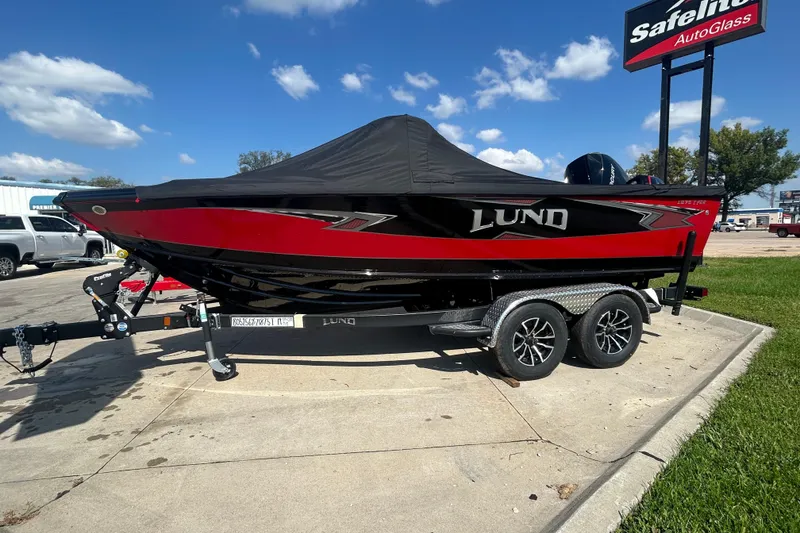 Slide: The Image of 2026 Lund 1875 Tyee boat on trailer, red and black design, parked outdoors. - 8