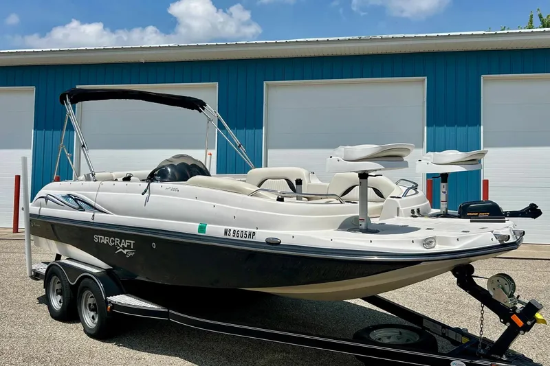 Slide: The Image of 2009 Starcraft Star Step boat on trailer, parked near blue building. - 2