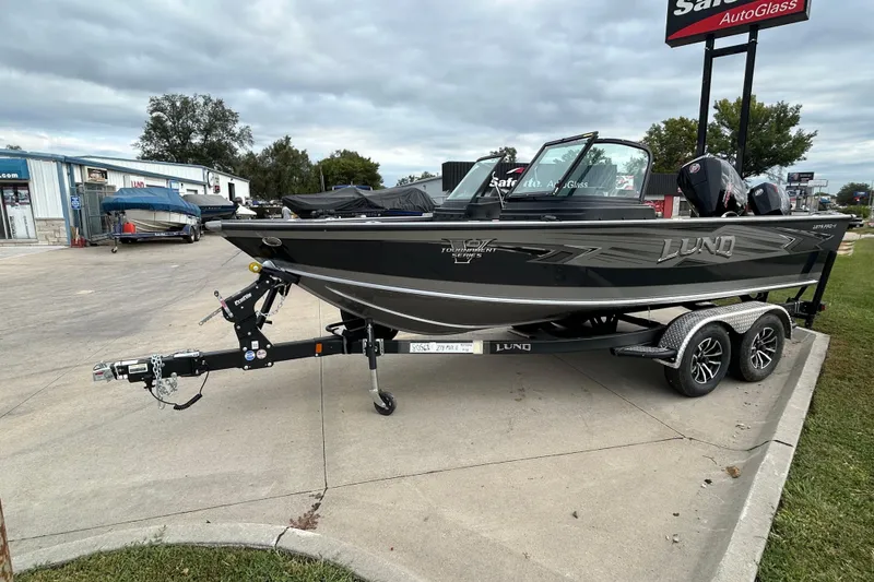 Slide: The Image of 2026 Lund 1875 Pro-V boat on trailer, parked outdoors near dealership. - 2
