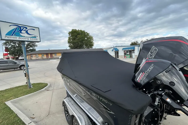 Slide: The Image of 2026 Lund 1875 Pro-V boat with cover at Premier Boating Center parking lot. - 5